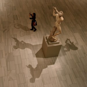 photo of the shadows of a statue and a museum visitor