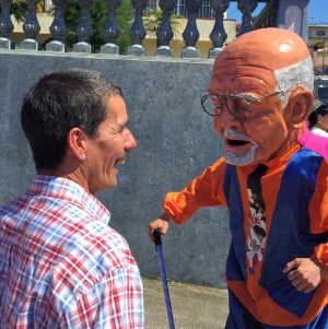 Photo of a man and a Masquerade character smiling at each other.