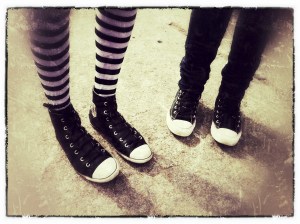 Photo of the legs from two young women wearing sneakers and striped leggings.