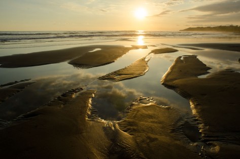 Photo of a sunset with sand pools very close to the camera showing hyperfocal focusing. Photo by Eduardo Libby