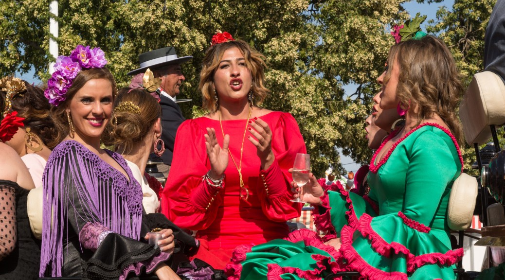 Image of three women wearing flamenco dresses while entering the Seville Fair on a horse carriage. Photo by Eduardo Libby