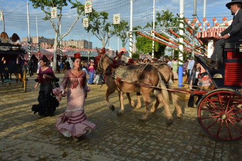 Image of young women in traditional dress and horse carriages at the Seville's Fair. Photo by Eduardo Lubby.